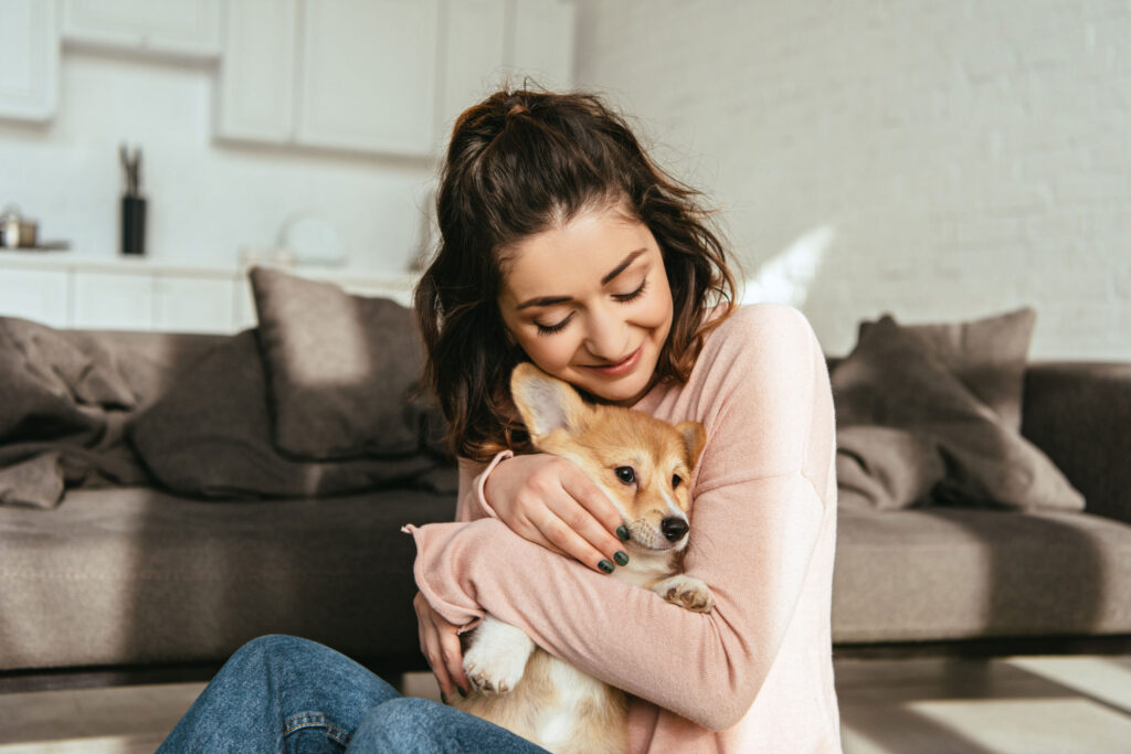 woman hugging corgi puppy